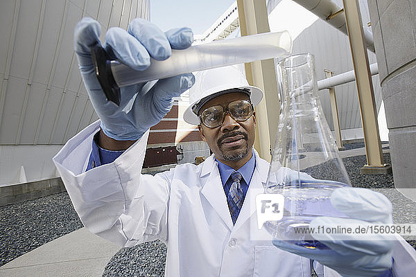 Wissenschaftler  der Flüssigkeit aus einem Messzylinder in einen Kolben gießt