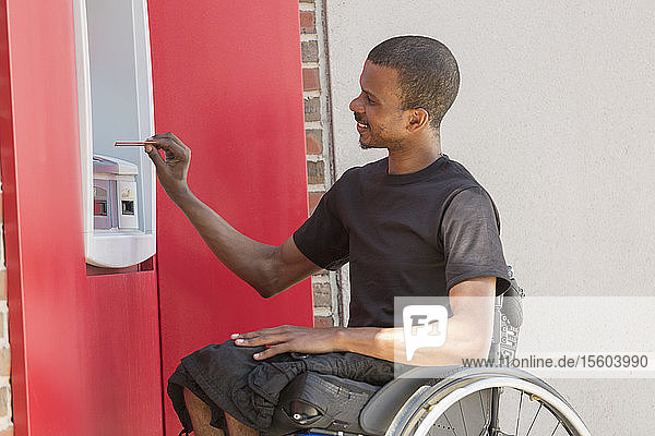 Man in a wheelchair who had Spinal Meningitis using a bank ATM