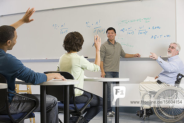 Universitätsprofessor mit Muskeldystrophie fragt seine Studenten in einem Klassenzimmer