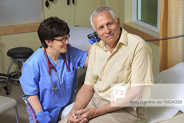 Krankenschwester mit Zerebralparese prüft die Ohren eines Patienten in einer Klinik