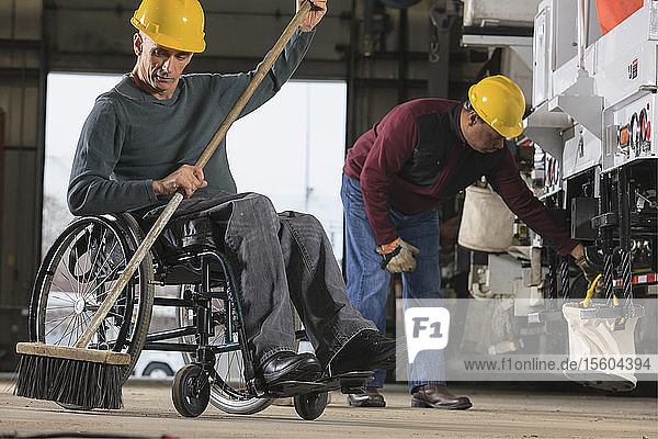 Maintenance technicians  one with a spinal cord injury  cleaning in utility truck garage at electric power plant