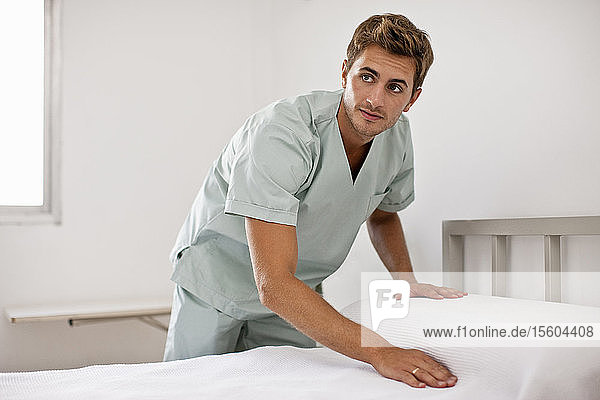 Krankenpfleger macht Krankenhausbett.