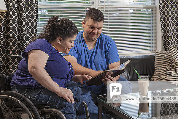 Woman with Spina Bifida looking at a photo album with her husband in living room