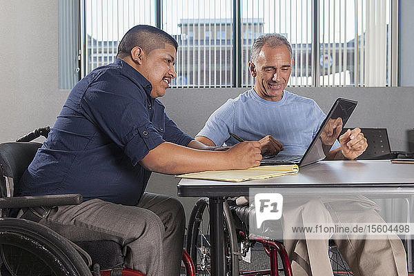 Two men with Spinal Cord Injuries working in an office