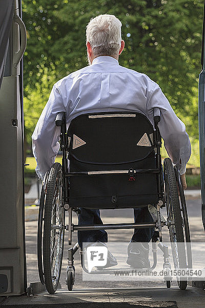 Geschäftsmann mit Muskeldystrophie im Rollstuhl beim Aussteigen aus seinem Lieferwagen auf dem Parkplatz