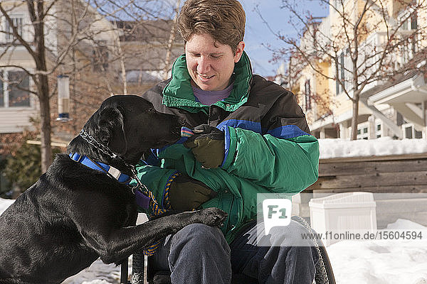 Frau mit Multipler Sklerose übergibt Schlüssel an einen Diensthund im Schnee