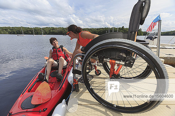Instructor helping a woman with a Spinal Cord Injury get into a kayak