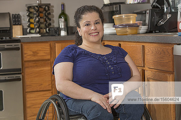 Porträt einer glücklichen Frau mit Spina Bifida in einem Rollstuhl in der Küche