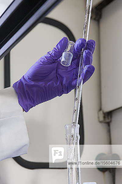 Laborwissenschaftler  der eine Pipette benutzt  um ein Reagenz für eine chemische Analyse hinzuzufügen
