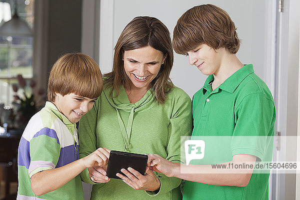 Frau und ihre beiden Söhne benutzen ein Tablet