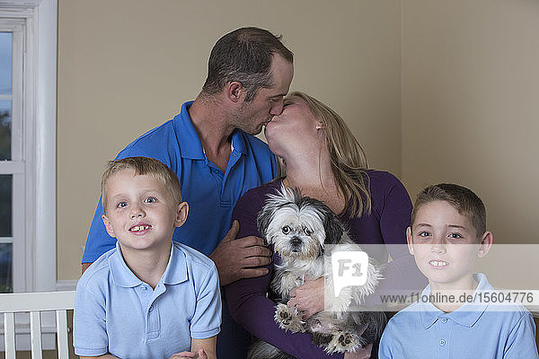 Porträt einer glücklichen Familie mit Hörbehinderung und küssenden Eltern