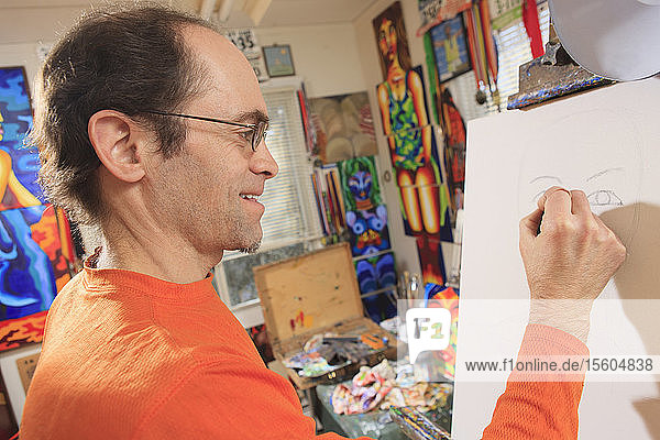 Mann mit Asperger-Syndrom  der in seinem Atelier den Umriss für sein Gemälde zeichnet