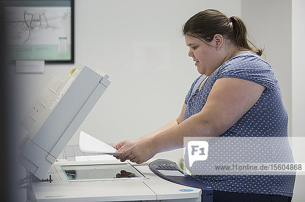 Frau mit einer Lernbehinderung benutzt einen Kopierer im Büro