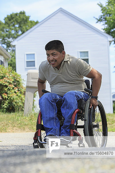 Hispanoamerikanischer Mann mit Rückenmarksverletzung im Rollstuhl vor seinem Haus