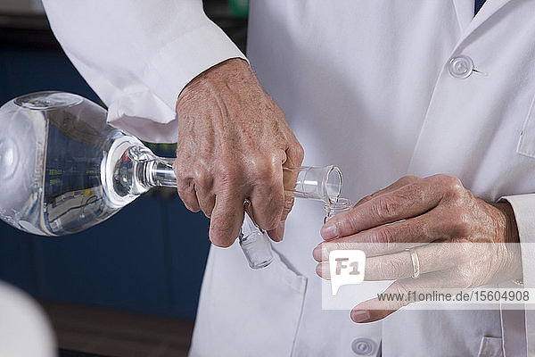 Wissenschaftler gießt Flüssigkeit aus einem Kolben in ein Fläschchen im Labor einer Wasseraufbereitungsanlage