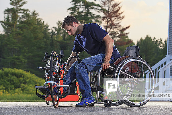 Ein Mann mit einer Rückenmarksverletzung in seinem Rollstuhl steigt auf sein speziell angefertigtes adaptives Handbike