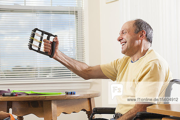 Mann mit Friedreich-Ataxie im Rollstuhl bei der Verwendung von Handkraftgeräten
