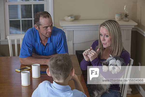 Familie mit Hörbehinderung sagt in amerikanischer Zeichensprache Sport mit einem Hund zu Hause