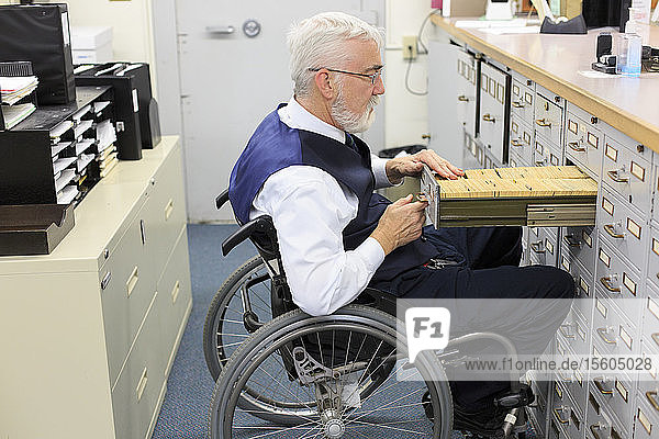 Man with Muscular Dystrophy in a wheelchair working in an office