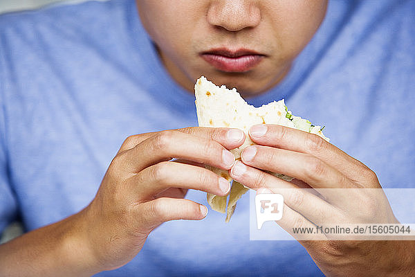 Nahaufnahme eines Mannes  der ein Sandwich isst.
