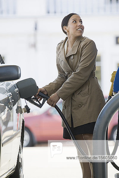 Hispanische Frau beim Betanken eines Autos an einer Tankstelle