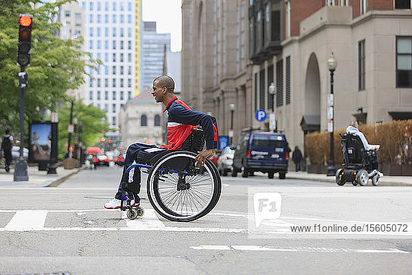 Mann im Rollstuhl  der an Spinaler Meningitis erkrankt ist  überquert eine Straße in der Stadt