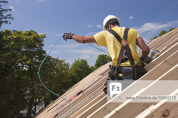 Ein spanischer Zimmermann entwirrt einen Luftschlauch an einem im Bau befindlichen Haus