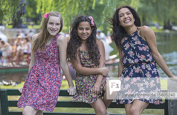 Portrait of happy Hispanic mother and two teen daughters in the park