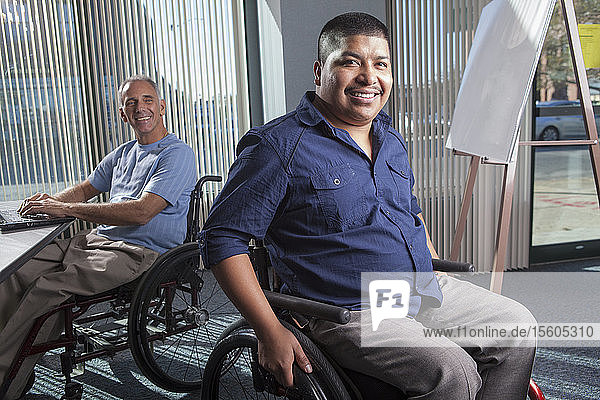 Zwei Männer mit Rückenmarksverletzungen arbeiten in einem Büro