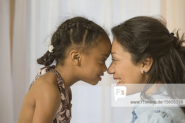 Hispanische Frau reibt sich die Nasen mit ihrer Tochter