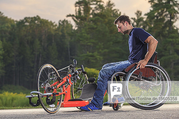 Man with spinal cord injury in his custom adaptive hand cycle getting into his wheelchair