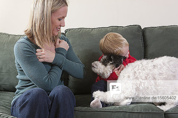 Frau  die das Wort Umarmung/Liebe in amerikanischer Zeichensprache gebärdet  während ihr Sohn einen Hund umarmt
