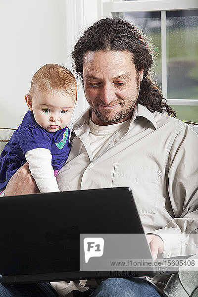 Vater und Baby schauen zu Hause auf den Computer