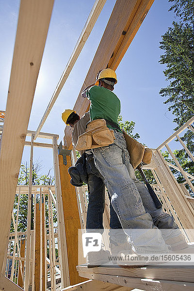 Carpenters lifting a laminated beam at a construction site