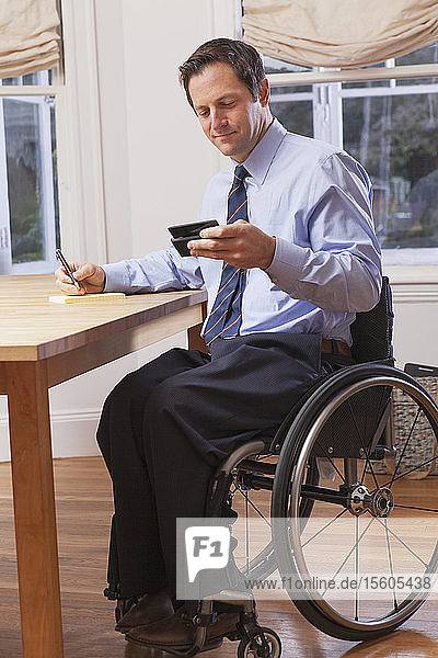 Businessman with spinal cord injury in a wheelchair using a smartphone