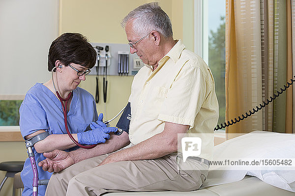 Krankenschwester mit Cerebralparese am Stock prüft den Blutdruck eines Patienten