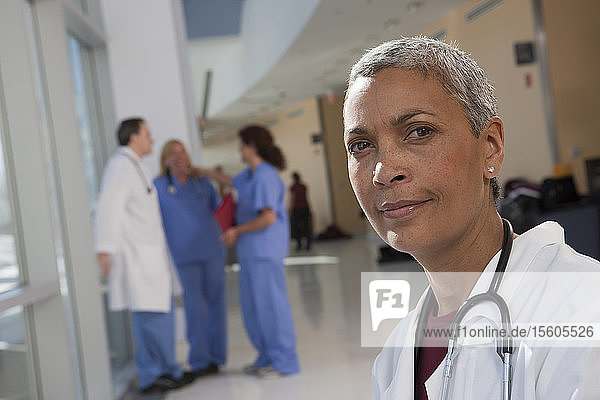 Porträt einer Ärztin mit ihren Kollegen im Hintergrund