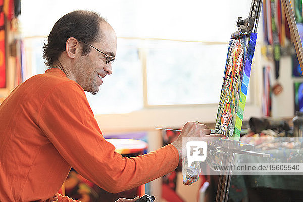 Man with Asperger's painting in his art studio