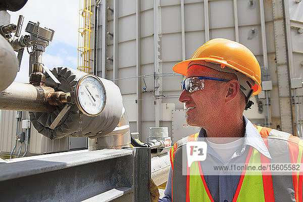 Engineer examining transducer gauge at electric power plant