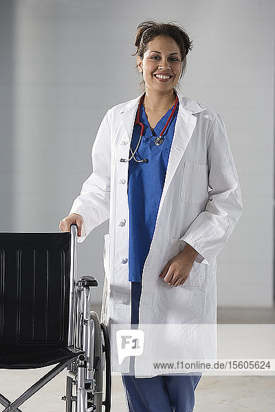 Porträt einer lächelnden Krankenschwester mit einem Rollstuhl