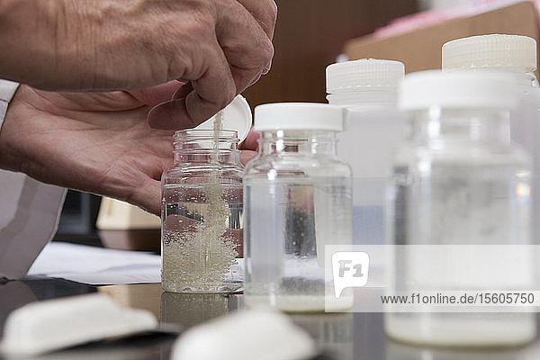 Wissenschaftlerin beim Mischen von Chemikalien in Probenflaschen im Labor einer Wasseraufbereitungsanlage