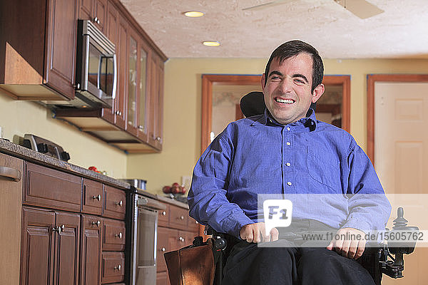Mann mit zerebraler Lähmung in seinem motorisierten Rollstuhl in seiner Küche