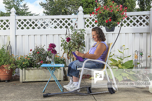 Frau mit Spina Bifida arbeitet auf der Terrasse am Tablet