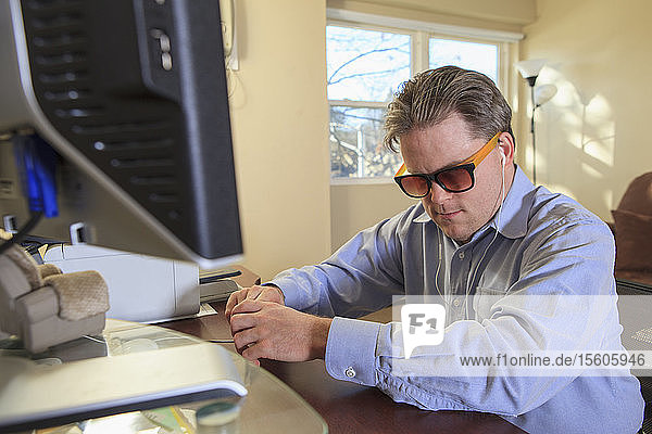 Ein Mann mit angeborener Blindheit nutzt Hilfsmittel an seinem Computer  um zuzuhören