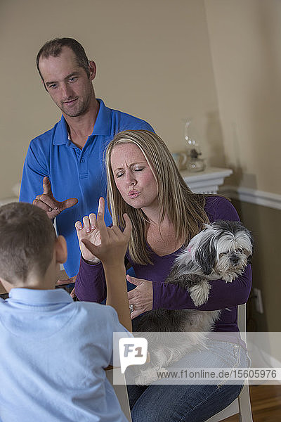 Familie mit Hörbehinderung sagt in amerikanischer Zeichensprache Ich liebe dich mit einem Hund zu Hause