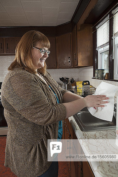 Eine blinde Frau wäscht sich in ihrer Küche die Hände