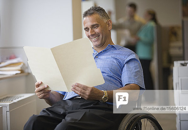 Mittlerer Erwachsener  der im Rollstuhl sitzt und ein Dokument liest