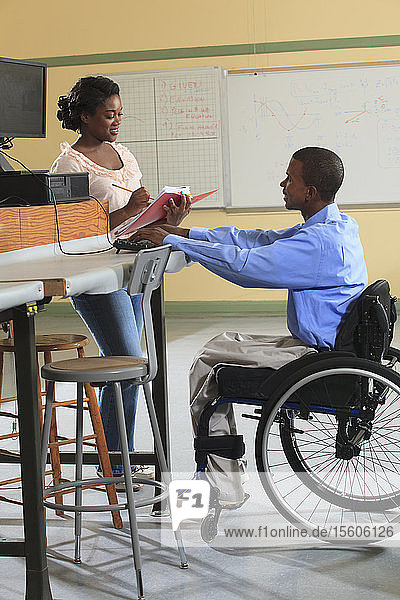 Engineering students in an electronics classroom  one in a wheelchair  working with a PC on laboratory bench