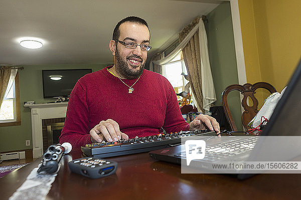 Mann mit Sehbehinderung an seiner Tastatur mit einem Bildschirmlesegerät