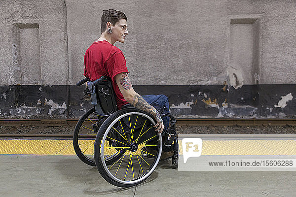 Trendiger Mann mit einer Rückenmarksverletzung im Rollstuhl  der auf einen U-Bahn-Zug wartet